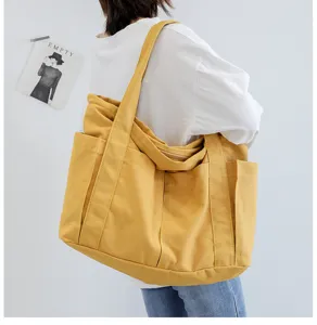Detailed view of large yellow canvas tote bag showing side pocket design and shoulder wear.