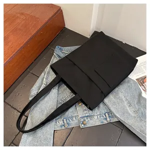 Detailed view of the black canvas tote bag, featuring large capacity, front pocket, and straps.