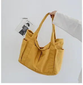 Yellow canvas tote bag detail view showing multi-pocket design and durable fabric structure.