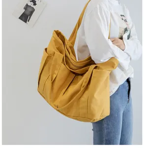 Close-up detail view of the yellow canvas tote bag featuring multiple external pockets.
