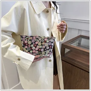 Detail shot of a compact floral cosmetic pouch featuring colorful woven flowers and a secure zipper closure.