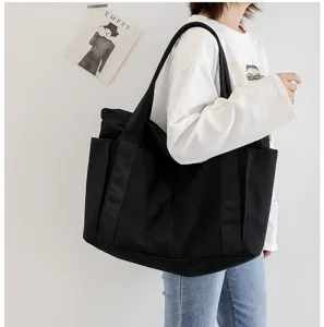 Detailed view of large black canvas tote bag, shoulder bag with side pockets for daily use.