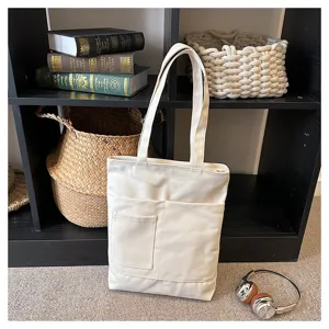 Detail view of a beige canvas tote bag with multiple front pockets and sturdy shoulder straps.