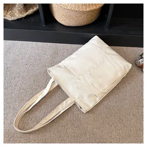 Beige canvas tote bag detail view, large capacity with multiple pockets and zipper closure.