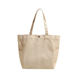 Casual beige canvas tote bag with side pockets and magnetic snap closure for daily commuting.