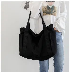 Black canvas tote bag detail view, casual large capacity shoulder bag for daily use.