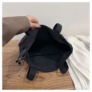Black canvas tote bag detail view showing interior pocket and smooth zipper closure system.