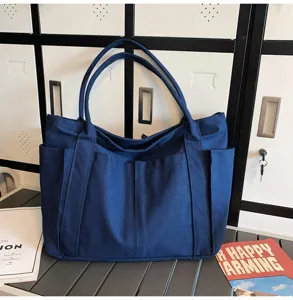 Blue canvas tote bag with large capacity and front pockets, ideal for daily casual use.