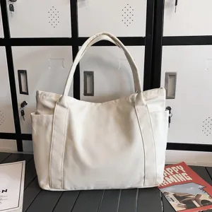 Detailed view of a stylish white canvas tote bag featuring convenient side pockets and handles.