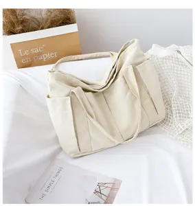 Detailed view of large capacity canvas tote bag with side pockets, casual minimalist style.