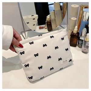 Corduroy cosmetic bag with black bows, portable makeup organizer pouch for women daily use.