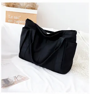 Black canvas tote bag detail showing large capacity, side pockets and durable straps.