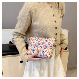 Detailed view of colorful rose pattern cosmetic makeup bag with brand logo label.