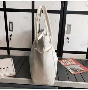 Detailed side view of a minimalist white canvas tote bag with side pocket and sturdy handles.