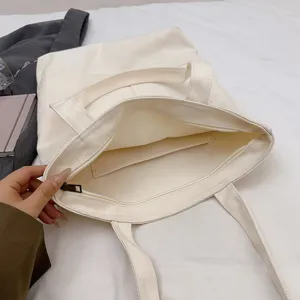 Spacious canvas shoulder bag with zipper closure, multi-pocket daily tote for women and students.