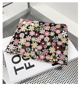 Close-up view of a chic floral woven cosmetic pouch with zip closure and stylish label detail.