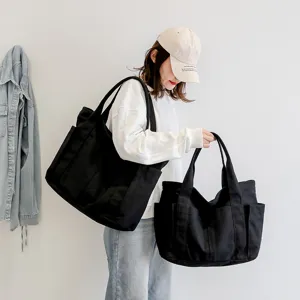 Simple black canvas tote bag for women, large capacity shoulder bag with multiple pockets.