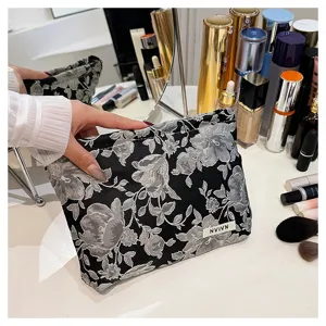 Detailed view of black and white floral woven cosmetic bag, portable makeup storage pouch.