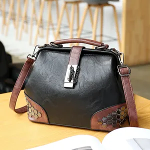 Black brown doctor shoulder bag for women with metal lock, rivets and adjustable crossbody strap.