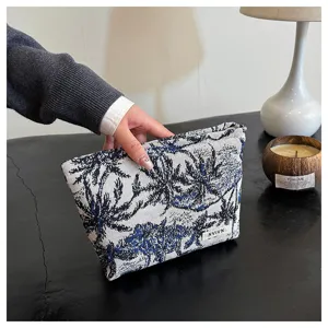 Fabric cosmetic bag detail view showing woven palm tree pattern texture and neat stitching quality.