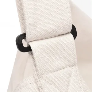 Detailansicht der Schultergurt-Schnalle einer weissen Segeltuchtasche mit robuster Textur.