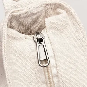 Weisse Canvas Tote Bag Metalldetail Reissverschluss Naht Baumwolle Material nah.