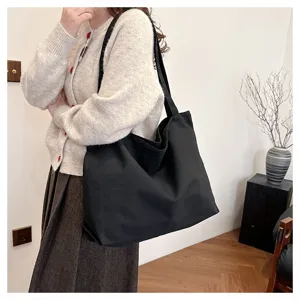 Detail view of the black canvas tote bag showcasing the spacious interior and shoulder strap.
