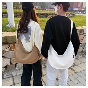 Prise de vue détaillée en extérieur présentant le grand sac bandoulière en toile bicolore.