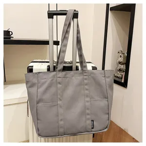 Grey canvas tote bag detail, casual daily shoulder bag hanging on luggage handle in room.