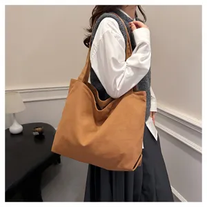 Detailed shot of a simple brown canvas tote bag worn by a model in a cozy indoor setting.