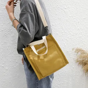 Yellow canvas shoulder bag for women, casual tote handbag with letter print and crossbody strap.