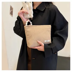 Detailed view of the beige corduroy cosmetic pouch, showing textured ribbed fabric.