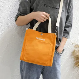 Orange canvas tote bag with front pocket and letter print, casual shoulder bag for daily use.