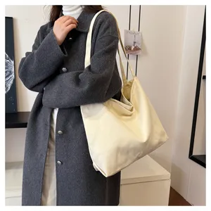 Detailed shot of a simple large capacity canvas tote bag worn by a model, casual daily style.