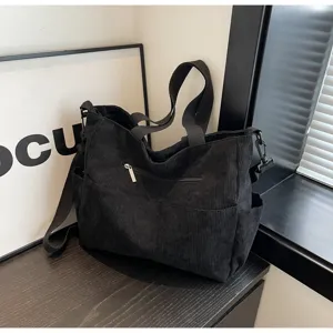 Black corduroy tote bag detail showing texture, zipper pocket, and sturdy shoulder straps.