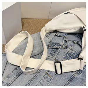 Gros plan détaillé du sac bandoulière en toile blanche avec sangle réglable et fermeture éclair.