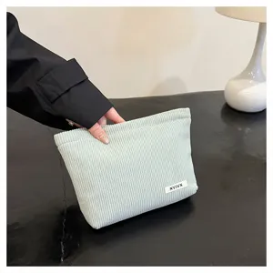 Corduroy cosmetic pouch detail in mint green, soft texture with mini label for everyday use.