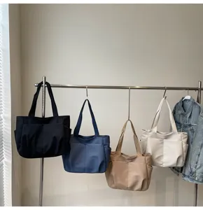 Minimalist solid color shoulder tote bag with multiple outer pockets for daily casual wear.