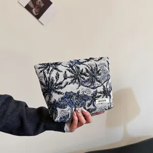 Vue détaillée de la trousse de toilette en tissu avec imprimé palmiers bleu et blanc.