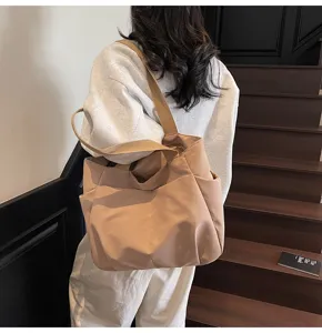 Detail view of minimalist beige canvas shoulder tote bag with wide strap and multi-pocket design.