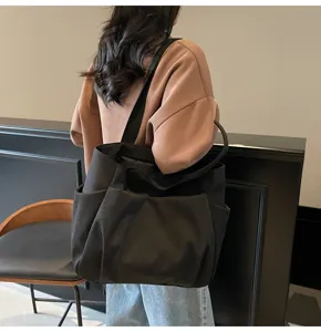 Black canvas shoulder tote bag, simple solid color design, large capacity casual daily bag detail.