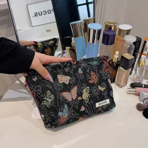 Detailed view of a black fabric makeup bag with colorful butterfly prints and brand label.