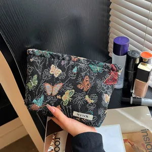 Close-up detail of the black fabric cosmetic bag featuring colorful woven butterfly patterns and zipper.