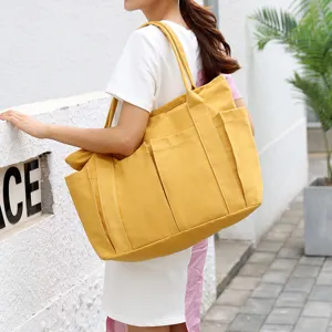 Detailed view of large yellow canvas tote bag with multiple exterior pockets for daily use.