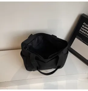 Minimalist black canvas tote bag shoulder bag with double handles and side pockets detail view