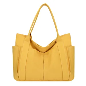 Detail view of yellow canvas tote bag showcasing front pockets and sturdy stitching structure.