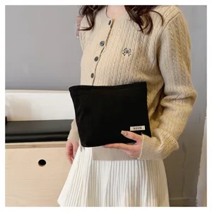 Black corduroy makeup pouch detail, soft texture clutch bag for daily storage needs.