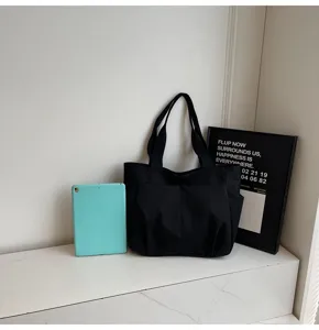 Minimalist black canvas tote bag detail view, casual solid color shoulder bag for daily use.