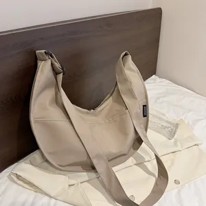 Detailed view of the khaki hobo crossbody bag featuring wide strap and practical front pockets.