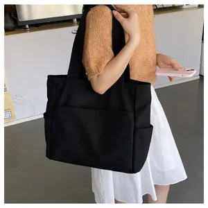 Black canvas tote bag detail view, casual large capacity shoulder bag showing daily wear style.
